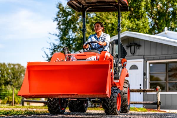 Woman driving BX2380 tractor with loader